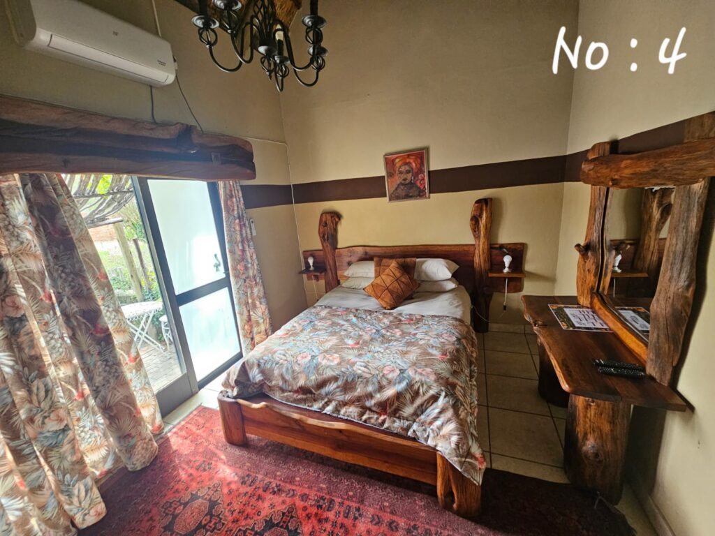 Cozy bedroom with natural wood finishes and glass doors opening to a patio at Pecan Guesthouse.