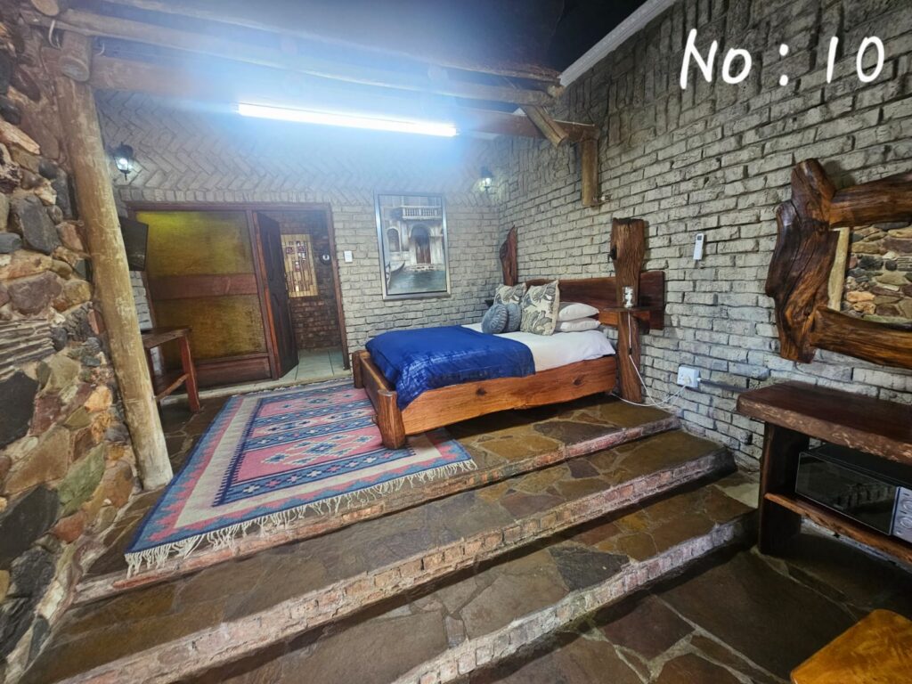 Elevated bedroom area with stone steps, rock walls, and a blue bedspread in Room 10.