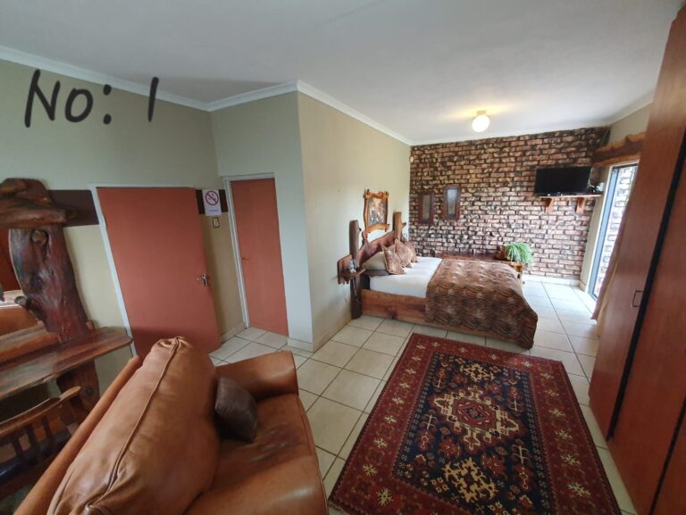 Rooms Leather armchair and patterned rug looking towards the bed in Room 1 at Pecan Guesthouse.